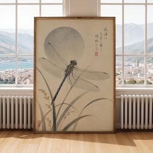 May include: A framed print of a dragonfly illustration. The artwork features a detailed dragonfly with transparent wings, perched on tall grass, set against a soft, circular moon. The print has Japanese text and is in a wooden frame.