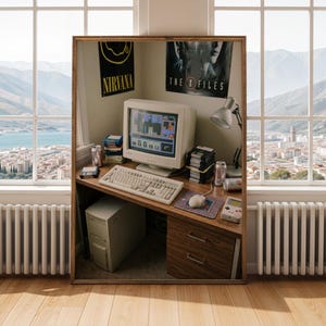 Op de afbeelding: Een ingelijste print van een retro computeropstelling. De bureau heeft een beige monitor, toetsenbord, muis en een stapel diskettes. Posters voor Nirvana en The X-Files zijn zichtbaar. Een Game Boy en een frisdrankblikje staan ook op het bureau.