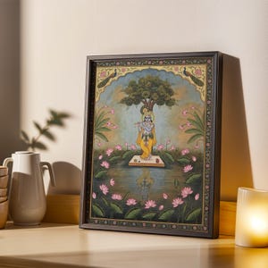 May include: Framed artwork showing a figure in yellow robes playing a flute, standing on a platform in a pond. The scene includes a tree, pink lotus flowers, and peacocks. The frame is dark brown.