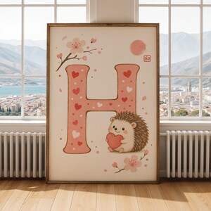 以下が含まれることがあります： ピンク色の「H」の文字がハートと点で飾られた、額入りのアートプリント。ハートを持ったかわいいハリネズミが文字の下にいます。桜とピンクの太陽が、この気まぐれで魅力的なデザインを完成させています。