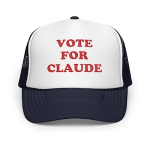 Può includere: Cappellino da camionista con pannello frontale bianco e visiera e retro in rete blu navy. Il testo "VOTE FOR CLAUDE" è stampato in rosso sul pannello frontale.