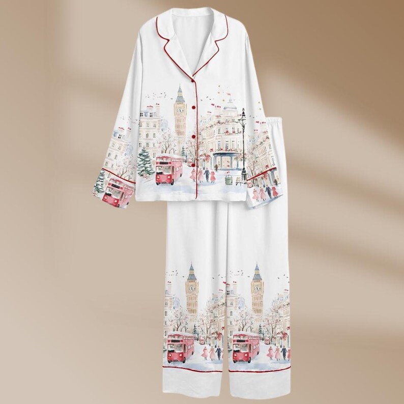 K&ouml;nnte beinhalten: Wei&szlig;es Pyjama-Set mit London-Motiv. Das lang&auml;rmlige Oberteil und die Hose zeigen ein Aquarelldesign von Big Ben, roten Doppeldeckerbussen und Geb&auml;uden. Das Set hat rote Verzierungen und Kn&ouml;pfe.