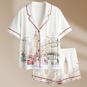 K&ouml;nnte beinhalten: Wei&szlig;es Pyjama-Set mit London-Motiv. Das kurz&auml;rmelige Oberteil und die Shorts zeigen eine Aquarellillustration von Big Ben, einem roten Doppeldeckerbus und anderen Londoner Wahrzeichen. Das Set ist mit roten Paspeln versehen.