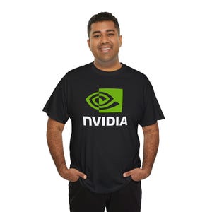 May include: Black t-shirt featuring the NVIDIA logo in green and white. The logo includes a stylized eye design within a green square, with the word "NVIDIA" printed below in white, sans-serif font. The shirt is a crew neck.