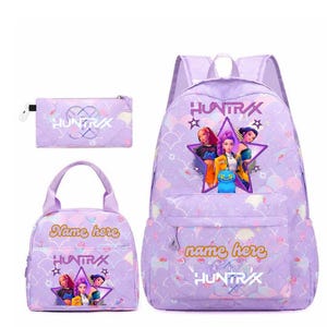 Może przedstawiać: Trzyczęściowy zestaw szkolny w jasnofioletowym kolorze, składający się z plecaka, torby na lunch i piórnika. Każdy element ma grafikę gwiazdy z postaciami z kreskówek oraz tekst "HUNTRAX" i "Name here".