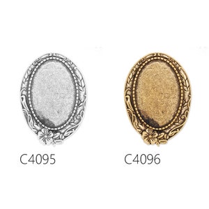 May include: Two oval-shaped metal picture frames with ornate floral designs. The frame on the left is silver and the frame on the right is gold. The frames are labelled C4095 and C4096.