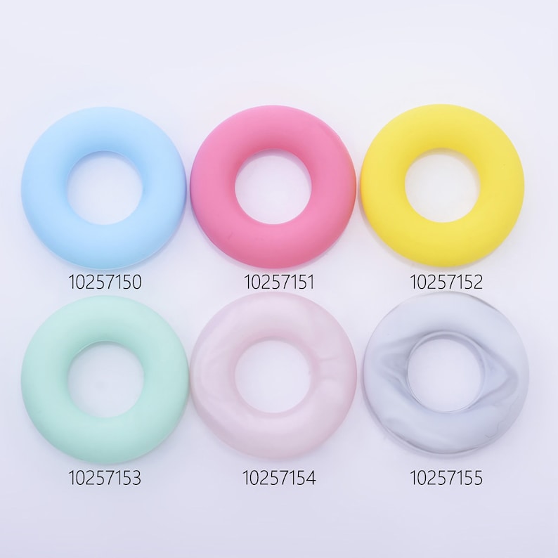 May include: Six silicone rings in different colors: light blue, pink, yellow, light green, light pink, and gray. Each ring has a smooth, rounded surface and a hole in the center. The rings are arranged in two rows of three, with the numbers 10257150, 10257151, 10257152, 10257153, 10257154, and 10257155 printed below each ring.