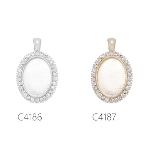 May include: Two oval-shaped pendant charms with a clear, flat surface and a border of small, clear rhinestones. The charm on the left is silver with a silver bail, and the charm on the right is gold with a gold bail. The charms are labelled C4186 and C4187.