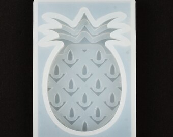 May include: A white silicone mold shaped like a pineapple. The mold has a detailed design of a pineapple with leaves and a textured pattern on the fruit.