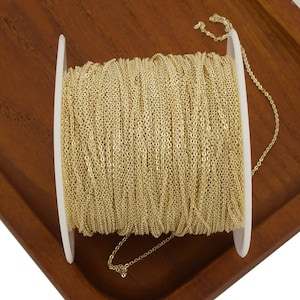 May include: A spool of gold-colored chain, wound around a white plastic spool. The chain is a delicate, fine-link style.