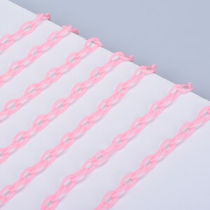 May include: Pink plastic chain links arranged in parallel lines on a white surface.