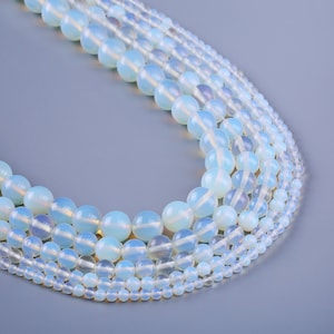 May include: A strand of white opal beads in various sizes. The beads are round and have a translucent, iridescent appearance.