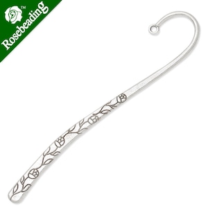 May include: Silver bookmark with a floral design. The bookmark has a curved end and a small loop at the top.