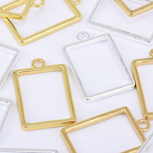 Puede incluir: Surtido de colgantes de marco de fotos de metal dorado y plateado con un bucle para colgar. Los marcos están vacíos y listos para resina u otros adornos.