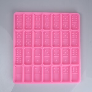 May include: Pink silicone mold with 28 individual domino-shaped cavities.