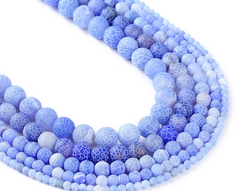 May include: A strand of blue agate beads in various shades of blue, ranging from light to dark. The beads are round and have a textured surface.