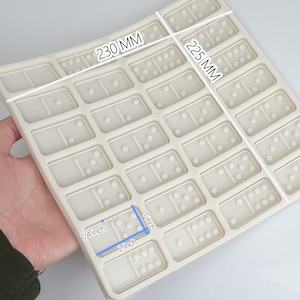 May include: A white silicone domino mold with 28 individual domino cavities. The mold measures 9.06 inches by 8.86 inches.