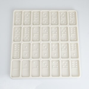 May include: White silicone mold with 28 individual cavities shaped like dominoes. The mold is designed for making chocolate or candy dominoes.