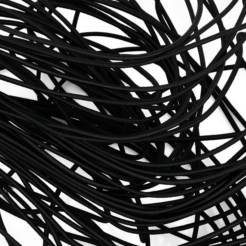 May include: A close-up of a bundle of black elastic cord. The cord is tightly wound together, creating a textured and interwoven pattern.