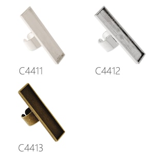 May include: Three silver, black, and gold-toned metal ring blanks with a rectangular shape. The blanks are designed to be filled with resin or other materials.