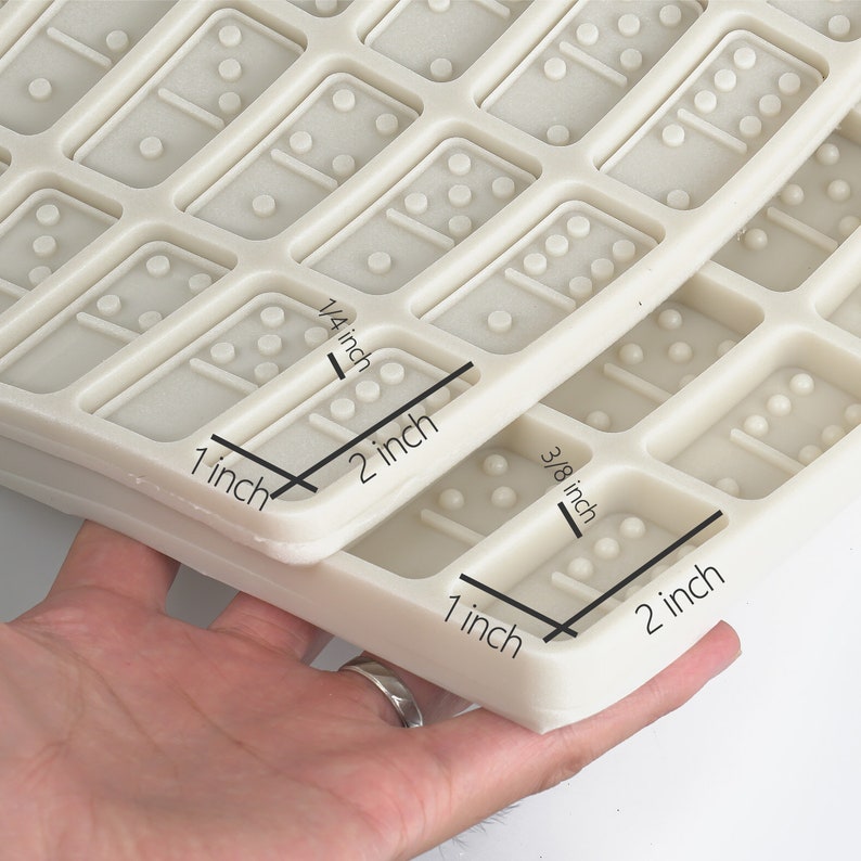 May include: White silicone mold for making dominoes. The mold is 2 inches wide and 1 inch tall. Each domino is 1/4 inch thick and 3/8 inch tall.