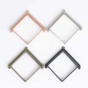 May include: Four square-shaped metal frames with a beaded edge. The frames are in four different colors: rose gold, silver, bronze, and black.
