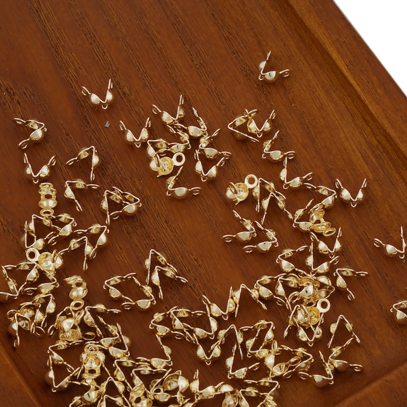 May include: A large quantity of gold-colored metal bead caps. The caps are designed to cover the ends of cords or strings.