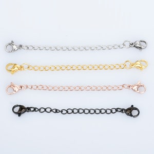 May include: Four necklace extender chains in silver, gold, rose gold, and black. Each chain has a lobster clasp on both ends and a small chain for adjustable length. The chains are displayed on a white background.
