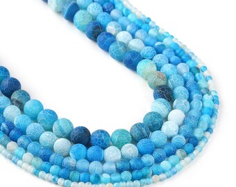 May include: A strand of blue agate beads in various shades of blue, from light to dark, with a crackled texture. The beads are round and smooth, and they are strung on a thin wire.