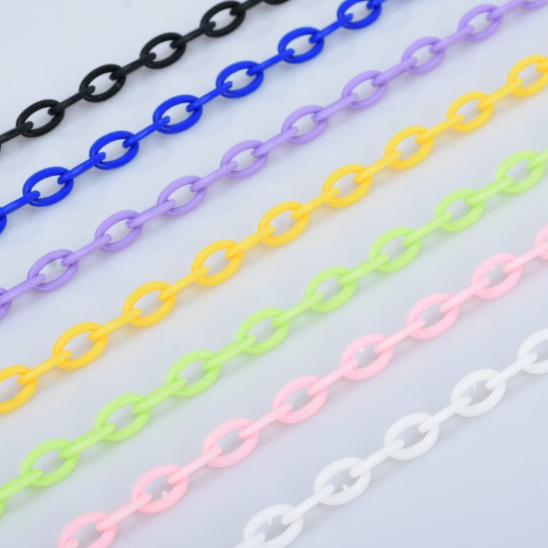 May include: A set of seven plastic chains in various colours, including black, blue, purple, yellow, green, pink, and white. The chains are all the same size and style, with oval-shaped links.