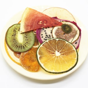 Könnte beinhalten: Ein Teller mit getrockneten Obstscheiben, darunter Kiwi, Wassermelone, Drachenfrucht, Orange und Limette.