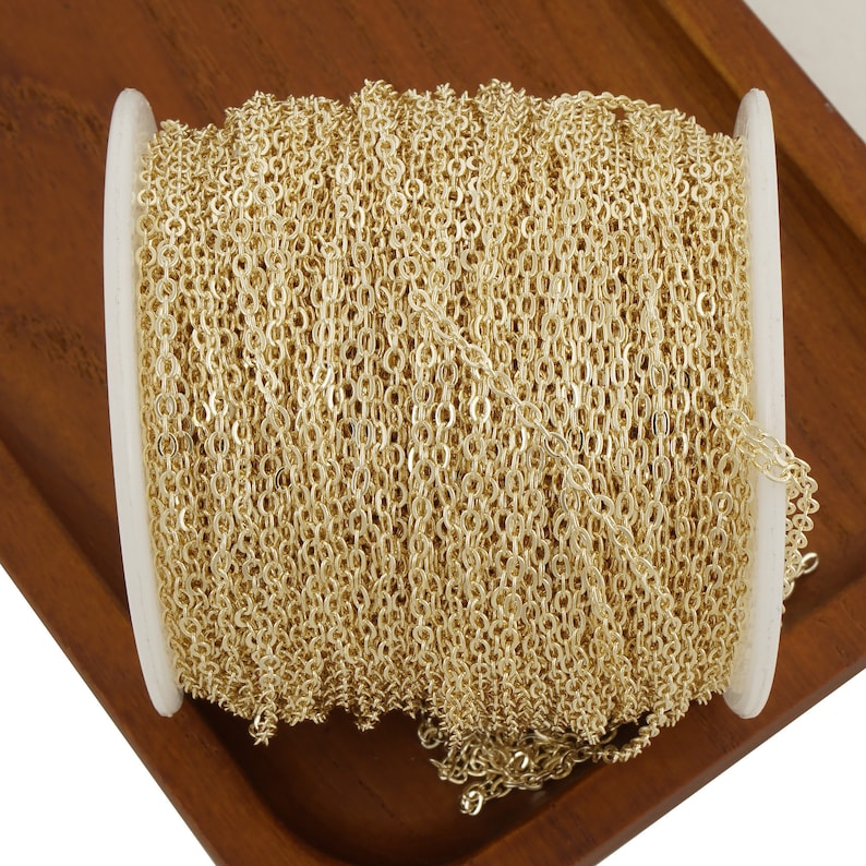 May include: A spool of gold-colored chain, wound tightly and ready to be used for jewelry making or other crafting projects.