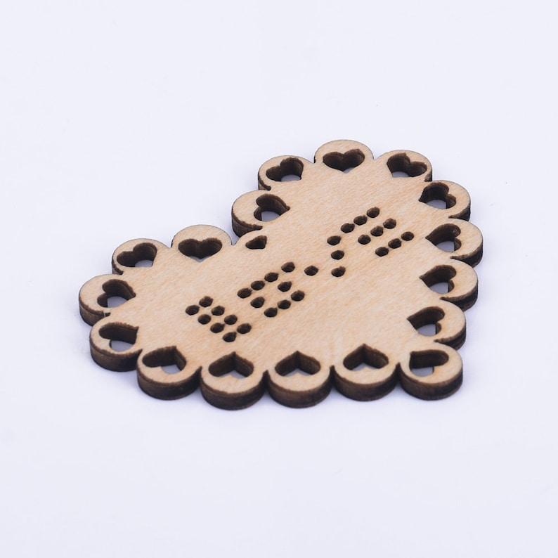 Puede incluir: Un adorno de madera en forma de coraz&oacute;n con un borde de encaje y la palabra "LOVE" escrita en peque&ntilde;os puntos.