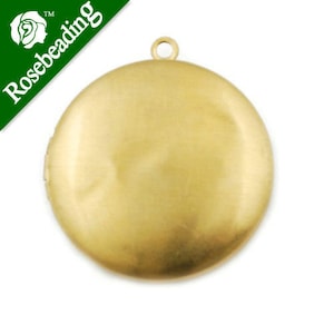 May include: A gold-toned metal locket pendant with a smooth, round surface and a loop at the top for attaching a chain.
