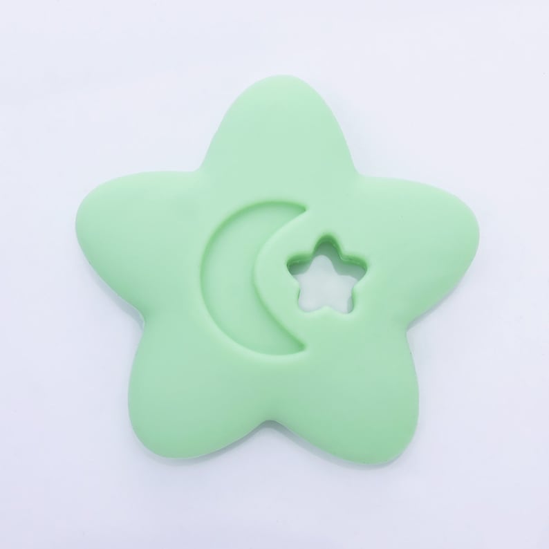 May include: A light green silicone baby teether shaped like a star with a crescent moon and a star cutout.