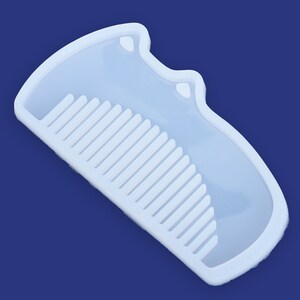 May include: A white silicone mold shaped like a comb with a cat-shaped handle. The mold is designed for making resin crafts.