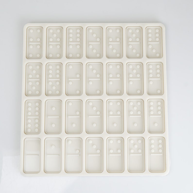 May include: A white silicone mold with 28 individual domino-shaped cavities. The mold is designed for making chocolate or candy dominoes.