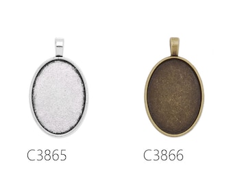 May include: Two oval-shaped metal pendant trays, one silver and one bronze, with a loop at the top for hanging. The trays are blank and ready for customization.
