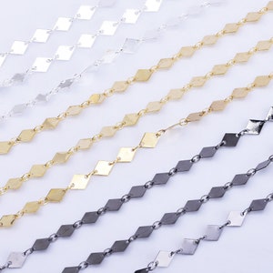 May include: Five strands of diamond-shaped chain in silver, gold, and black metal.