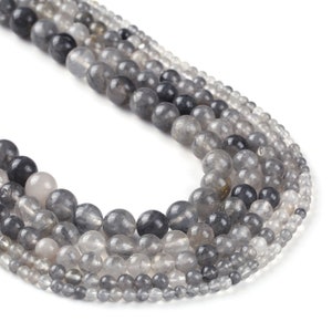 May include: A strand of gray and clear quartz beads. The beads are round and have a smooth, polished finish. The beads are strung on a clear elastic cord.