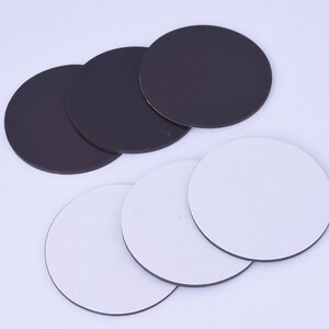 May include: A set of six round adhesive backed sticky pads. Three are black and three are white.