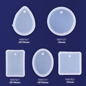 May include: Six clear silicone moulds for making resin jewellery pendants. The moulds are in various shapes, including a teardrop, circle, rectangle, oval, and square. Each mould has a small hole at the top for attaching a jump ring or bail.