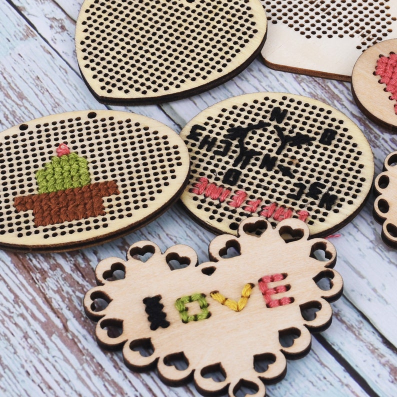 Puede incluir: Cinco aros de bordado de madera con diferentes dise&ntilde;os. Los aros son en forma de coraz&oacute;n, c&iacute;rculo y &oacute;valo. Los dise&ntilde;os incluyen un cactus, una br&uacute;jula y la palabra "LOVE".