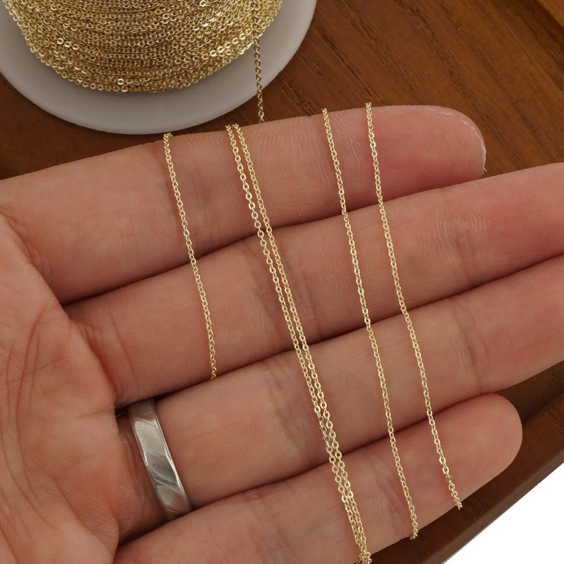 May include: Four lengths of gold chain are displayed on a hand. The chains are different lengths and are all the same thickness.