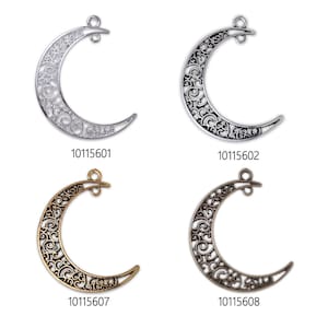 Puede incluir: Cuatro colgantes de media luna en plata, metal de cañón, oro y bronce. Cada colgante presenta un diseño calado con un patrón decorativo y un lazo en la parte superior para colgar. Los códigos de producto son visibles.