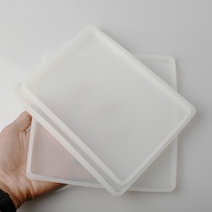 May include: Two white silicone molds for resin casting. The molds are rectangular and have a raised edge.