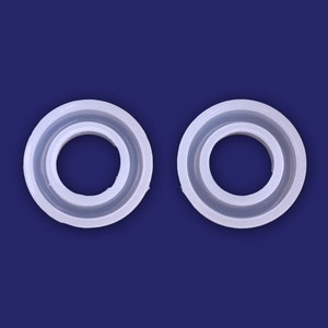 May include: Two white silicone rings, each with a smaller inner ring, are shown against a blue background.