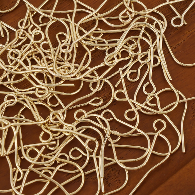 Puede incluir: Un mont&oacute;n grande de ganchos para pendientes de color dorado. Los ganchos son de metal y tienen un dise&ntilde;o simple y cl&aacute;sico.