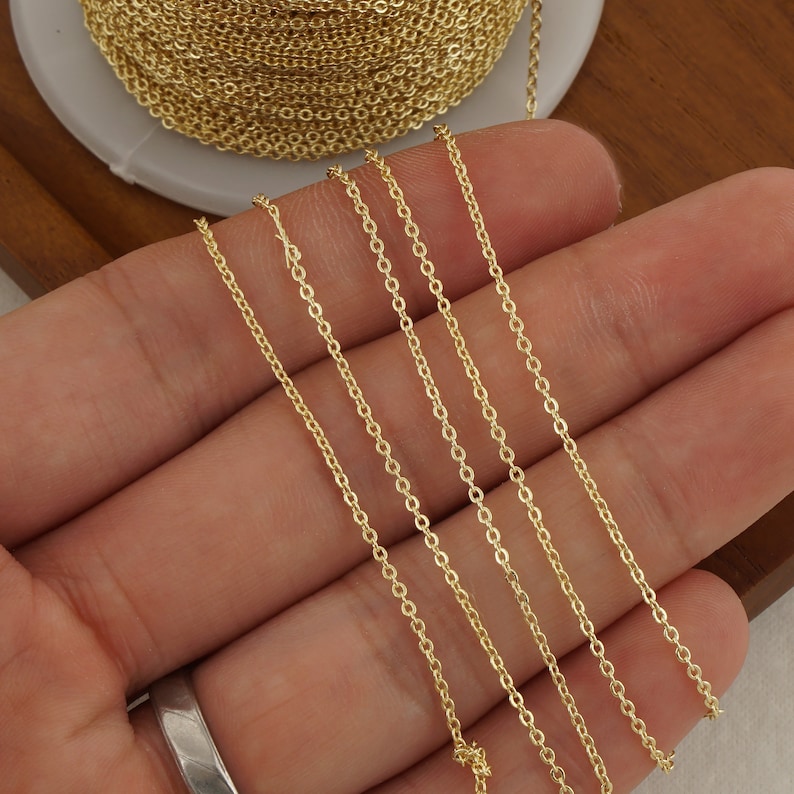 May include: Gold chain in various lengths, displayed on a hand. The chain is a delicate, fine link style.