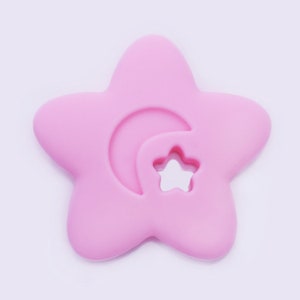 May include: A pink silicone baby teether shaped like a star with a crescent moon and a smaller star cut out.